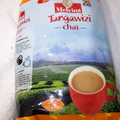 Melvins Tangawizi Chai 500g Kenyan ginger black tea bag with brewed spiced chai cup on tea farm background