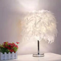 Modern chrome table light with white feather shade for bedroom